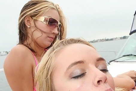 A blonde is sucking an unseen dick on a boat as another girl sits next to her.